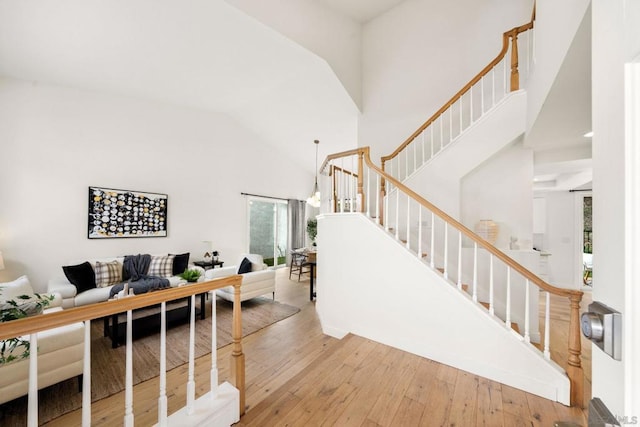 staircase with wood-type flooring and high vaulted ceiling