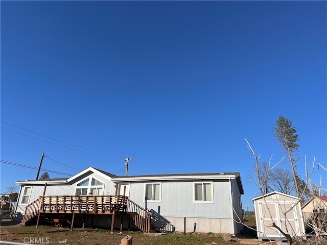 rear view of house featuring stairway, an outdoor structure, and a wooden deck