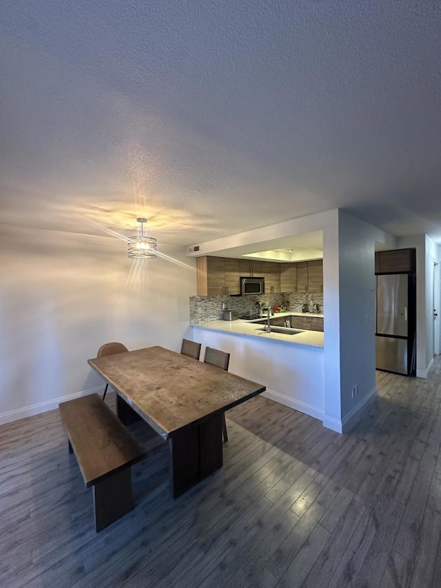 unfurnished dining area featuring sink, dark wood-type flooring, and a textured ceiling