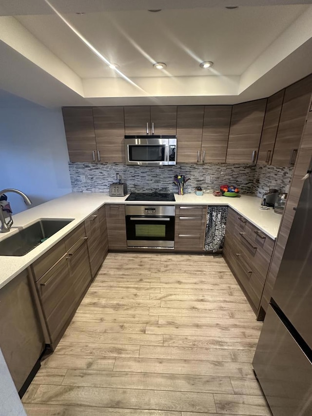 kitchen featuring tasteful backsplash, stainless steel appliances, light hardwood / wood-style floors, and sink