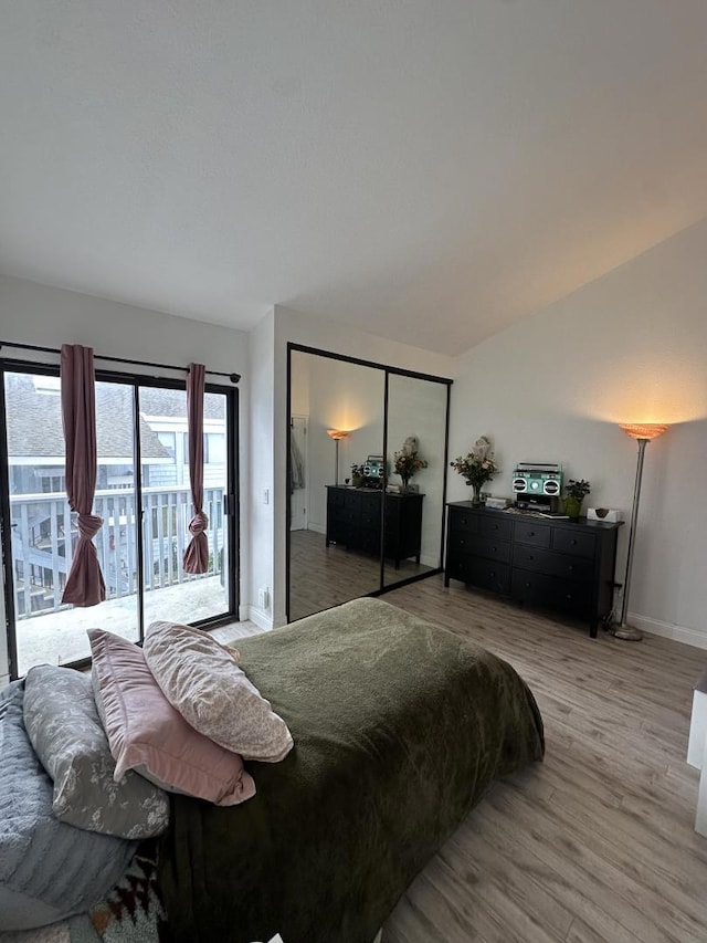 bedroom with lofted ceiling, access to exterior, and light hardwood / wood-style flooring