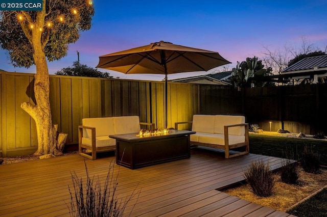 deck at dusk featuring an outdoor living space with a fire pit