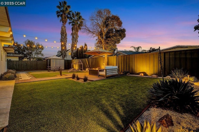 yard at dusk featuring an outdoor living space and a patio