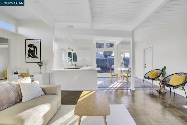 living room featuring plenty of natural light, beam ceiling, and parquet flooring