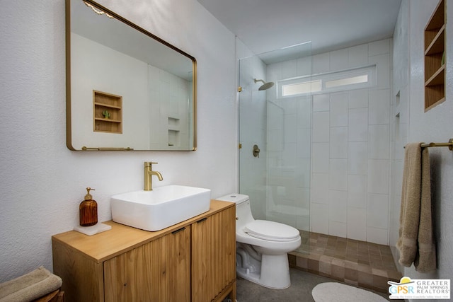 bathroom with tiled shower, vanity, and toilet