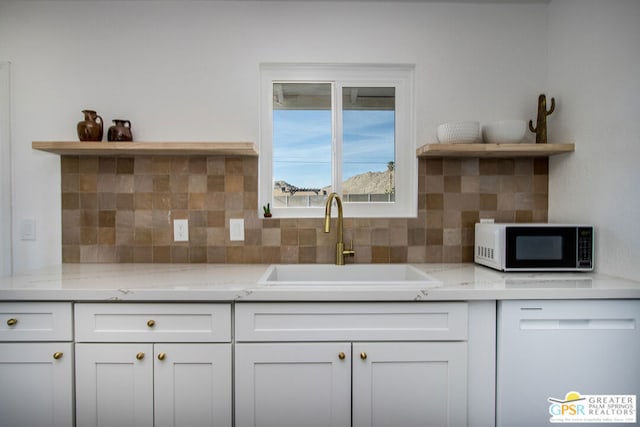 kitchen with white cabinetry, light stone countertops, sink, and decorative backsplash