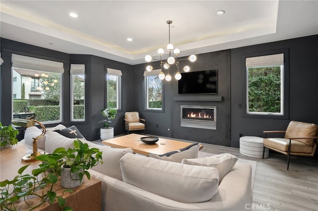 living room featuring light hardwood / wood-style flooring, a raised ceiling, and a chandelier