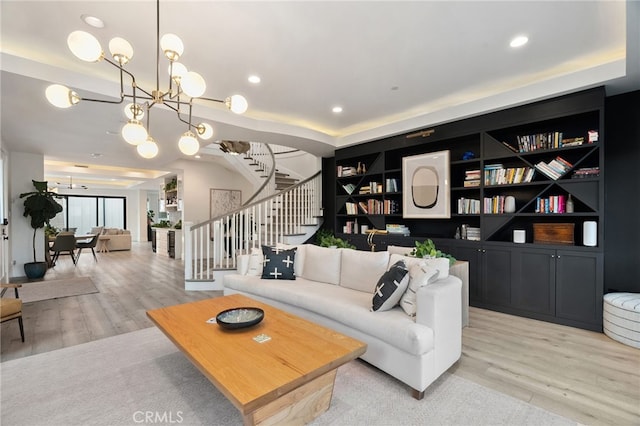 living room featuring built in shelves, light wood-type flooring, and a notable chandelier