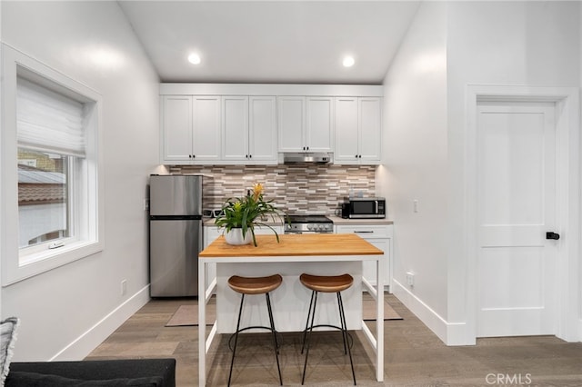 kitchen with stainless steel appliances, a breakfast bar, white cabinets, and backsplash