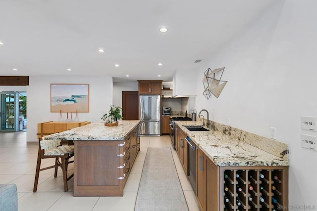 kitchen with light tile patterned flooring, sink, a center island, light stone counters, and stainless steel appliances