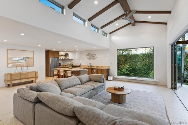 living room featuring sink, high vaulted ceiling, light tile patterned floors, beamed ceiling, and ceiling fan