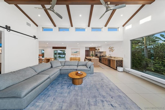 living room with light tile patterned flooring, high vaulted ceiling, beamed ceiling, ceiling fan, and a barn door