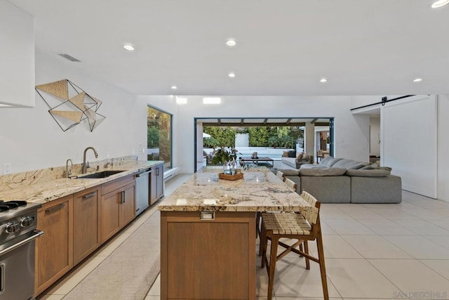 kitchen with sink, a breakfast bar, stove, a center island, and a barn door