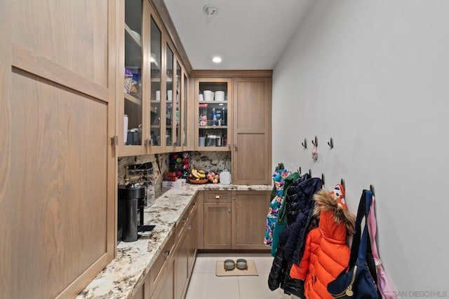 interior space featuring light tile patterned floors, backsplash, and light stone countertops