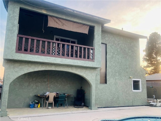 back house at dusk with a patio and a balcony