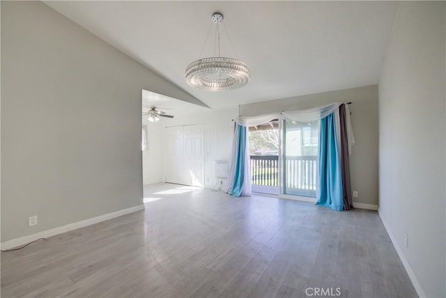 spare room with lofted ceiling, hardwood / wood-style floors, and an inviting chandelier