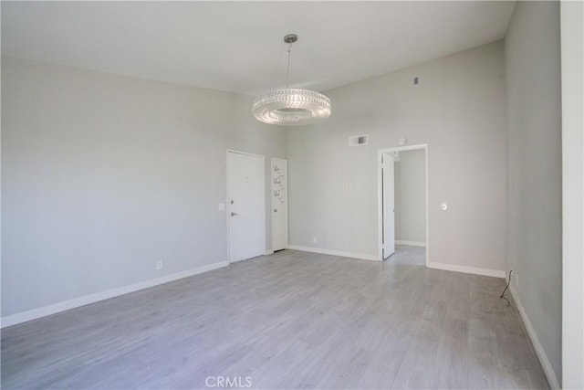 spare room with a towering ceiling and light wood-type flooring