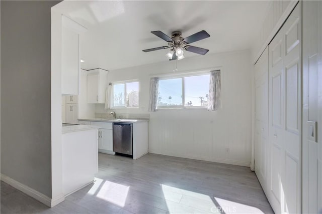 kitchen with sink, light wood-type flooring, stainless steel dishwasher, ceiling fan, and white cabinets