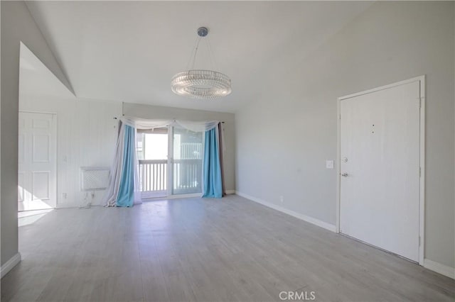 spare room with vaulted ceiling and light hardwood / wood-style flooring