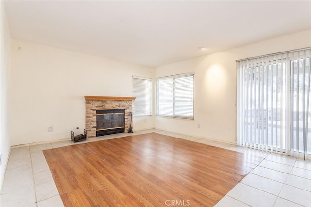 unfurnished living room featuring a stone fireplace and light tile patterned floors