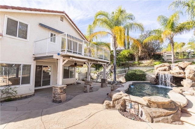 back of house with pool water feature, a balcony, ceiling fan, a fenced in pool, and a patio