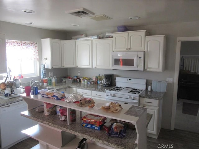 kitchen with light stone countertops, sink, white cabinets, and white appliances