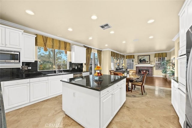 kitchen with a kitchen island, white cabinetry, appliances with stainless steel finishes, and sink