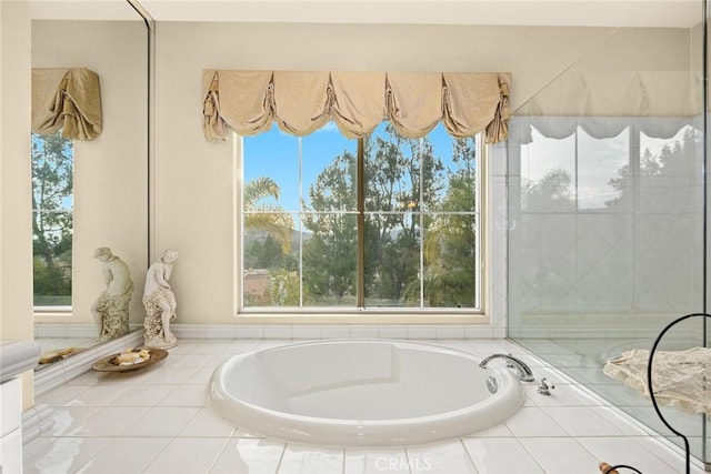 bathroom with a relaxing tiled tub and plenty of natural light