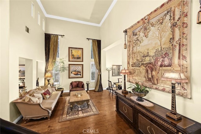 living area with a towering ceiling, ornamental molding, and dark hardwood / wood-style floors