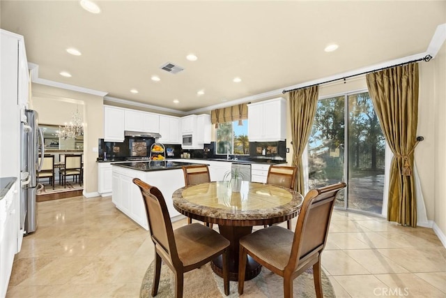 tiled dining space featuring an inviting chandelier, sink, and ornamental molding