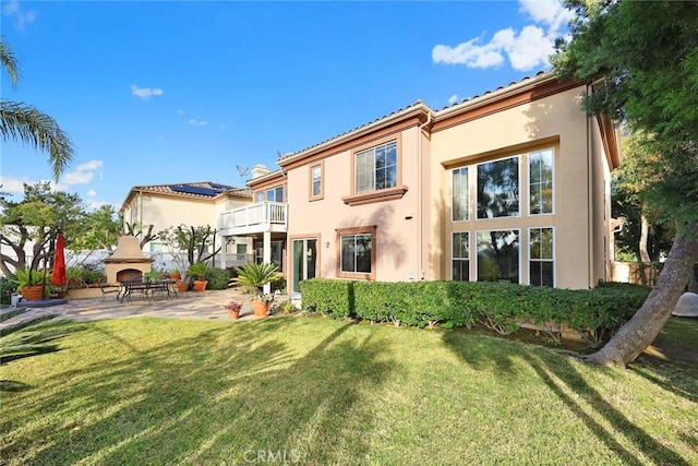 back of house with a patio area, a balcony, and a lawn