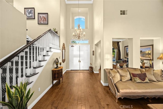 entrance foyer with a healthy amount of sunlight, dark hardwood / wood-style floors, a chandelier, and a towering ceiling