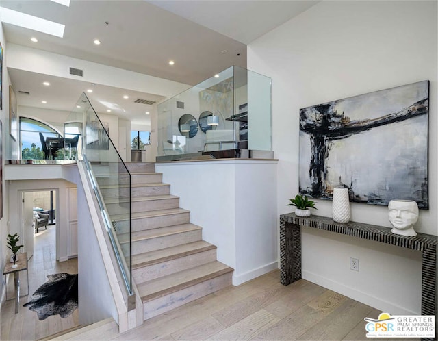 staircase featuring a skylight and hardwood / wood-style floors