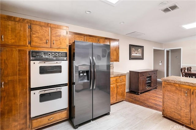 kitchen featuring double oven and stainless steel fridge with ice dispenser