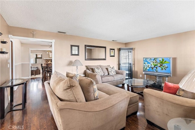 living room with ceiling fan, dark hardwood / wood-style floors, and a textured ceiling