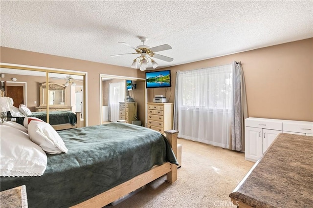 carpeted bedroom featuring ceiling fan, a textured ceiling, and two closets