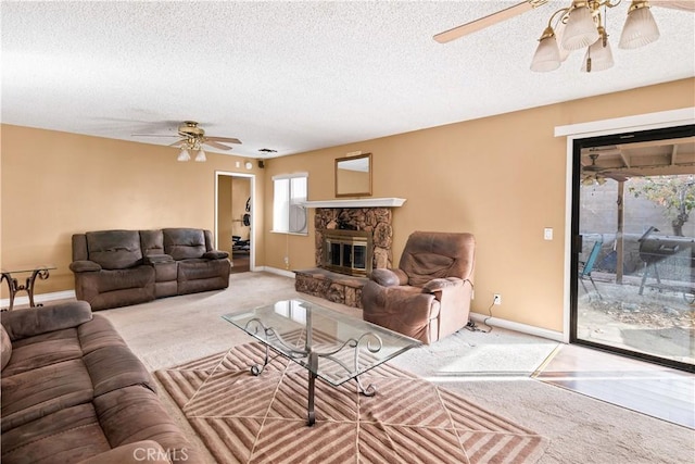 carpeted living room featuring a stone fireplace, a textured ceiling, and ceiling fan