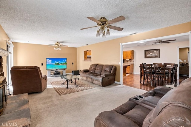 carpeted living room featuring a textured ceiling and ceiling fan