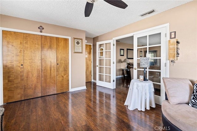 unfurnished room featuring dark hardwood / wood-style flooring, ceiling fan, french doors, and a textured ceiling