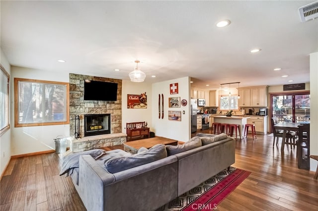 living room featuring dark hardwood / wood-style floors and a stone fireplace