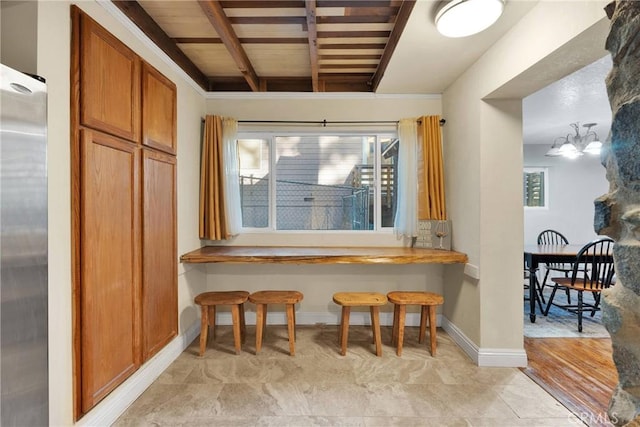 kitchen with a notable chandelier, beam ceiling, stainless steel fridge, and plenty of natural light