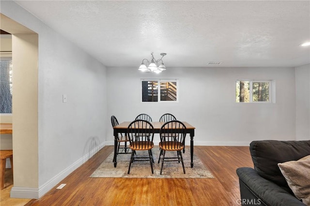 dining area featuring hardwood / wood-style floors, a textured ceiling, and an inviting chandelier