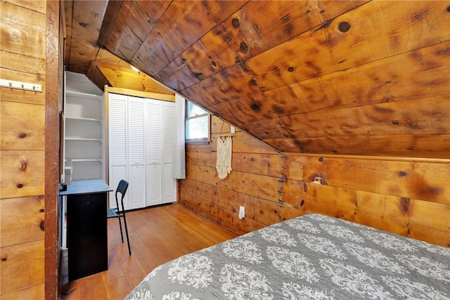 unfurnished bedroom with lofted ceiling, wooden walls, light hardwood / wood-style floors, and wooden ceiling