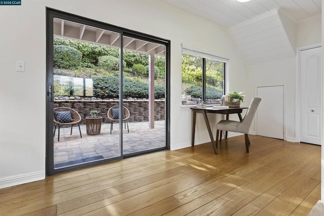 doorway featuring wood-type flooring and vaulted ceiling