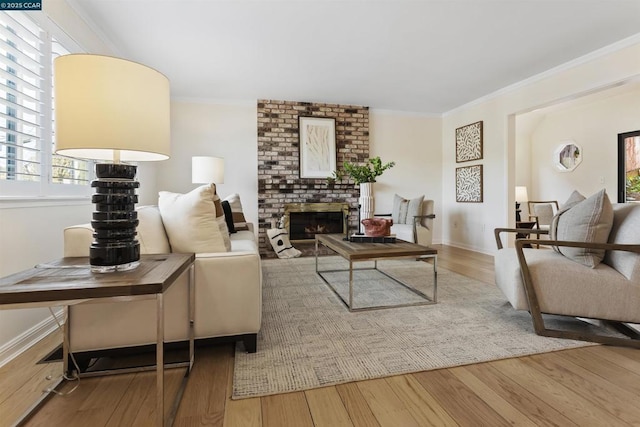 living room with ornamental molding, a brick fireplace, and wood-type flooring