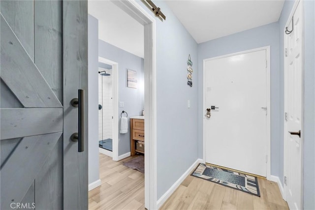 interior space featuring light wood-style floors, a barn door, and baseboards