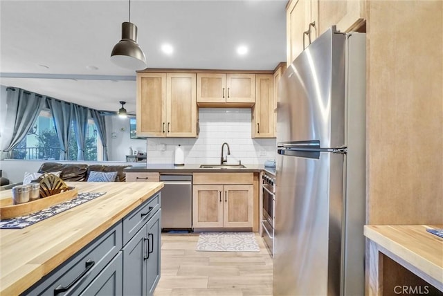 kitchen featuring light brown cabinets, stainless steel appliances, butcher block countertops, a sink, and decorative backsplash