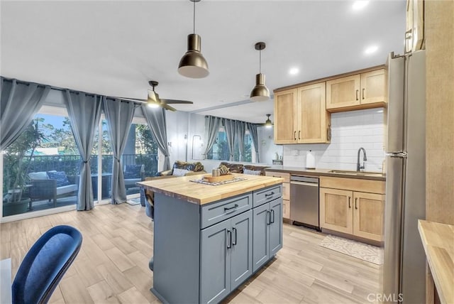 kitchen featuring light wood-style flooring, wood counters, a sink, stainless steel appliances, and backsplash