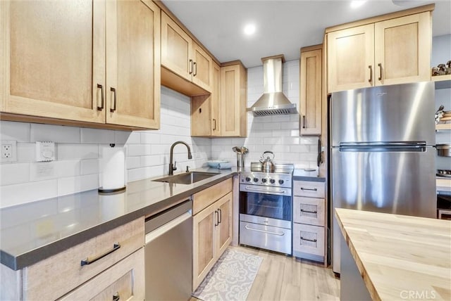 kitchen featuring stainless steel appliances, wall chimney range hood, a sink, and light brown cabinetry