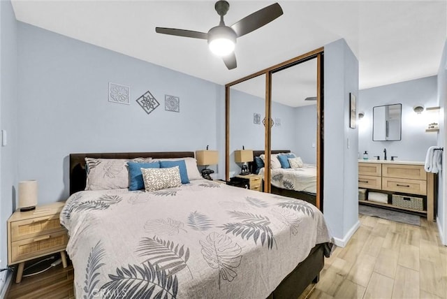 bedroom featuring light wood-type flooring, ceiling fan, a closet, and a sink